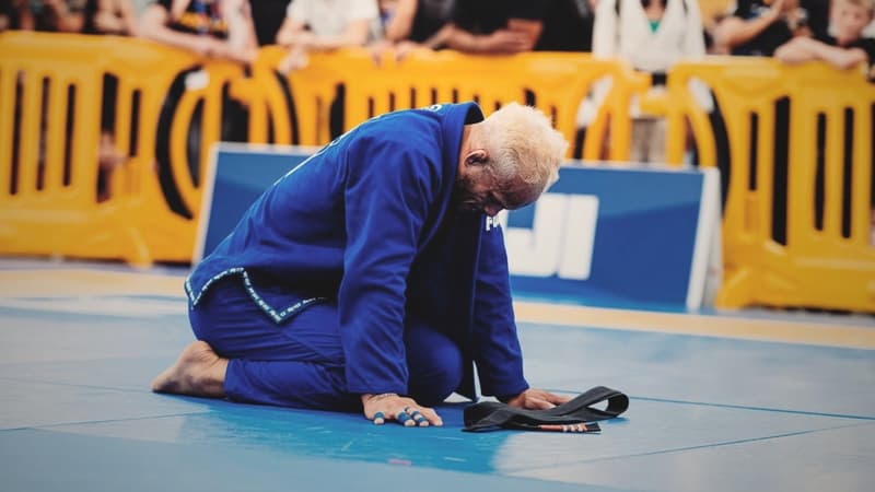 A gi competitor kneeling on the competition mat.