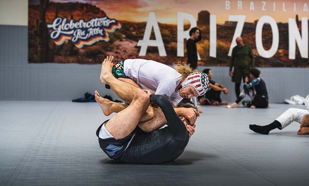 Two grapplers practicing on a mat at a BJJ Globetrotters camp.