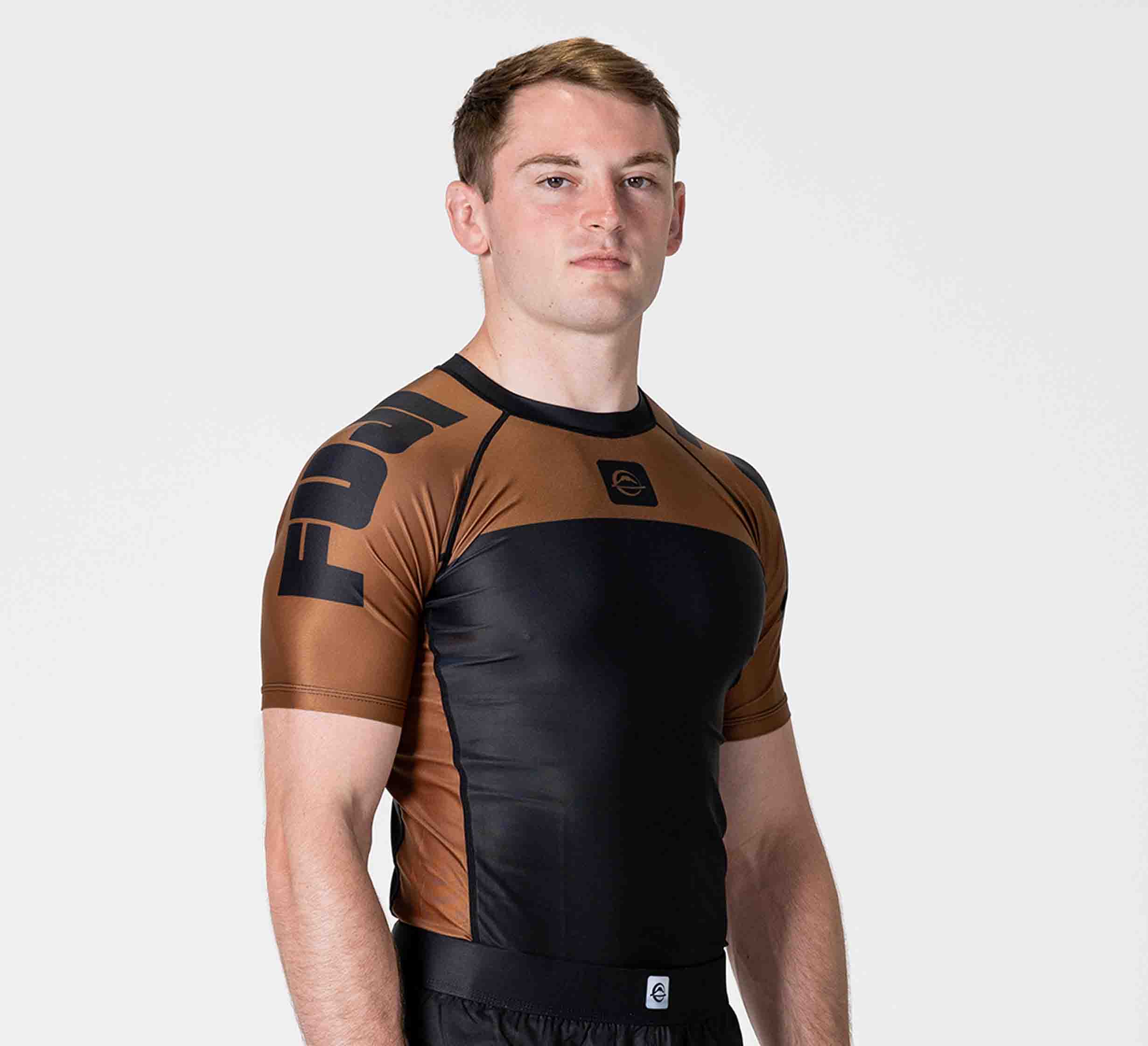 A model wearing a brown and black short-sleeved FUJI rashguard