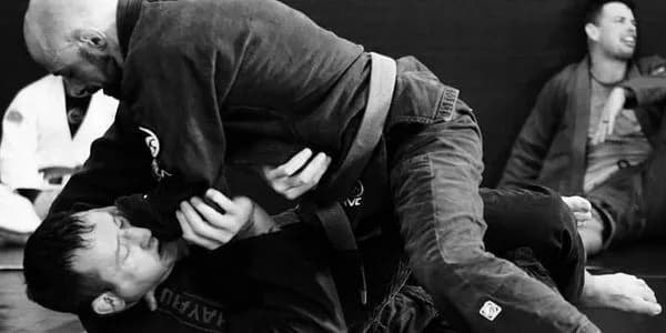 Two practitioners grappling on mats during Brazilian Jiu-Jitsu training, black-and-white photo.