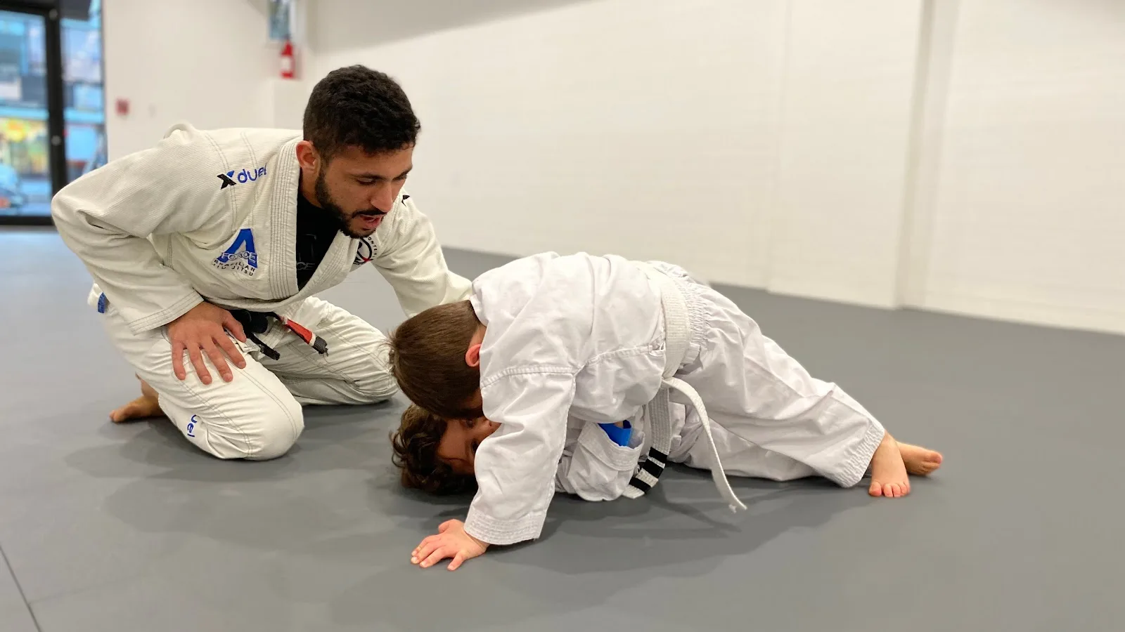 A-Force Brazilian Jiu Jitsu Academy in Rockville Centre, NY, featuring a trainer and two children practicing on the mat.