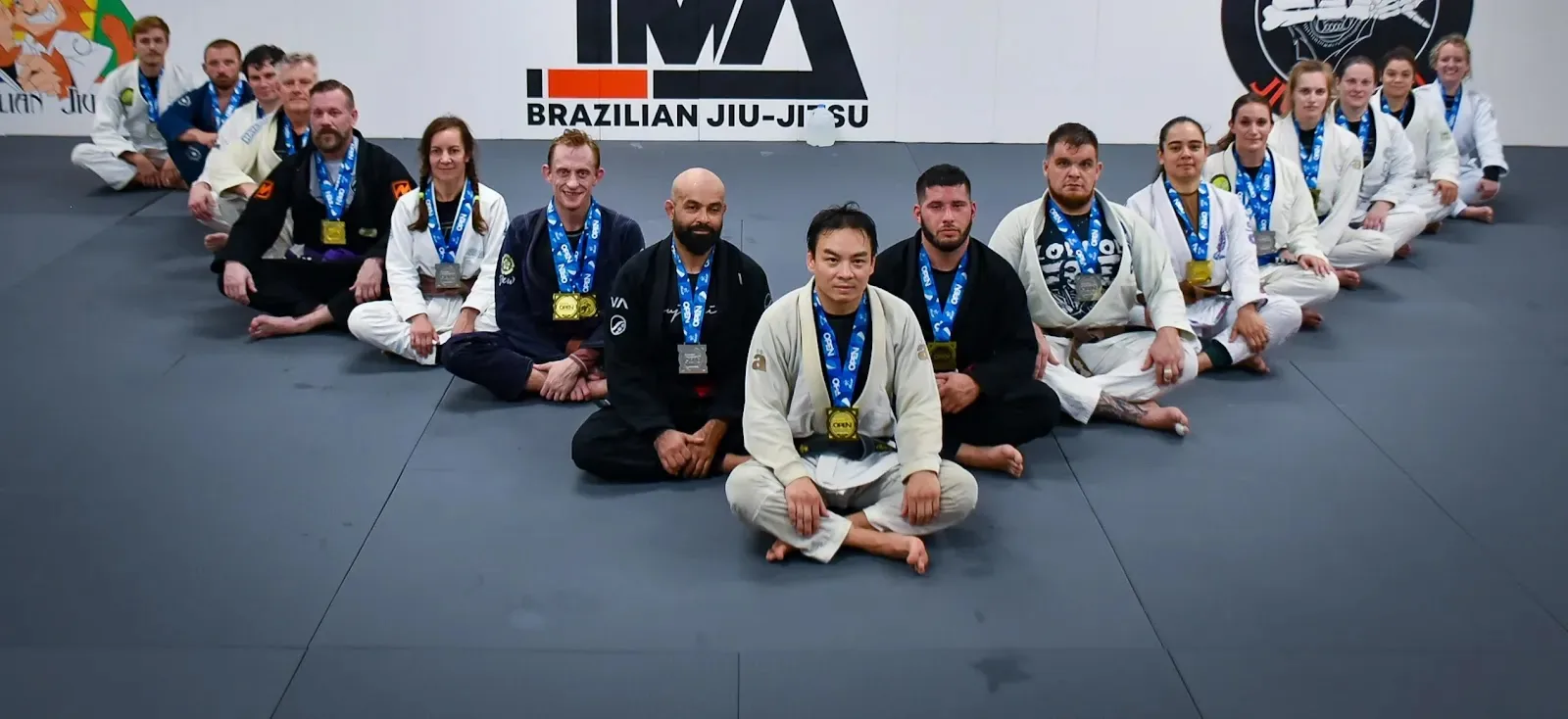 Group of students in BJJ gis sitting on mats at Top Martial Arts Charlotte in Pineville, NC.